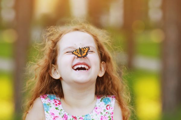 Laughing funny girl with a butterfly on his nose.